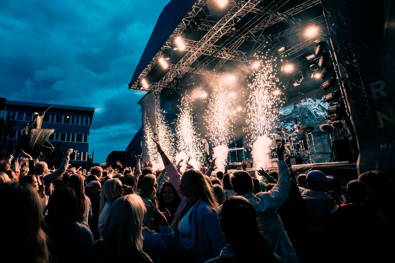 a large crowd at a concert on a bright day with firework